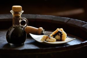 Balsamic Vinegar of Modena with Parmesan flakes set on plates and a wooden barrel