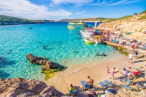 Beautiful beach with clear water and blue sky and sun, people enjoying the beach