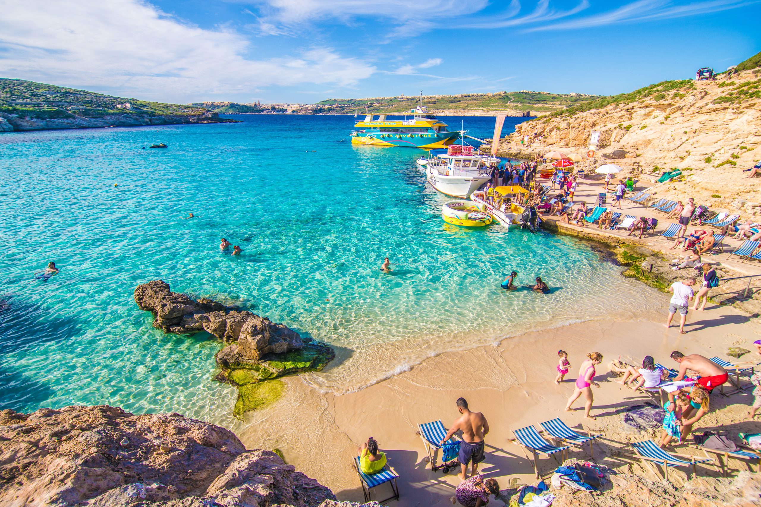 Beautiful beach with clear water and blue sky and sun, people enjoying the beach