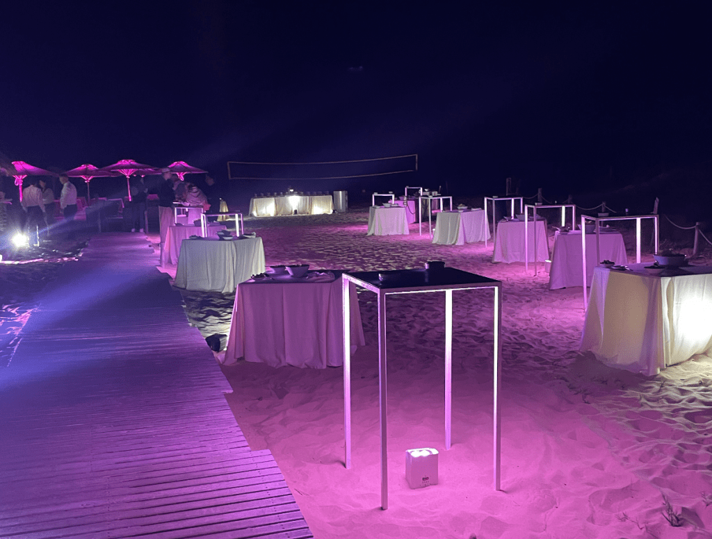 Event location on the beach at night, purple lights.