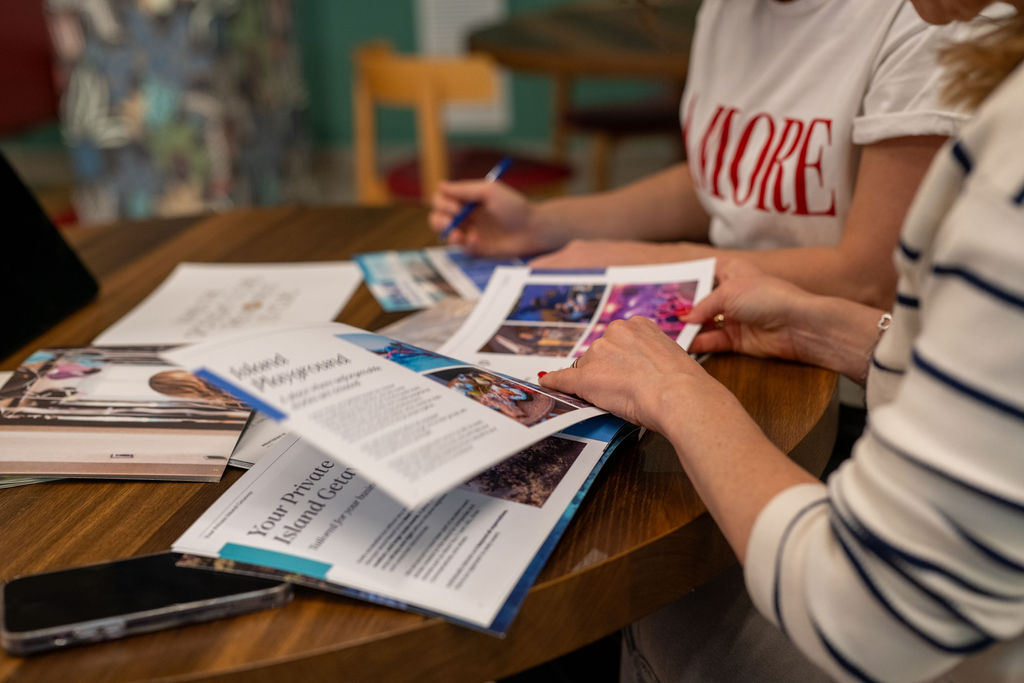 Travel planning with a catalog and two people reviewing it.