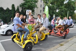 Group of people on yellow and red conference bikes in the city.