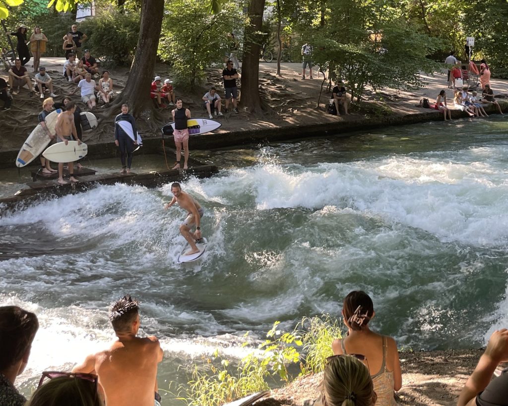 Surfer on the river in Munich, people are watching.