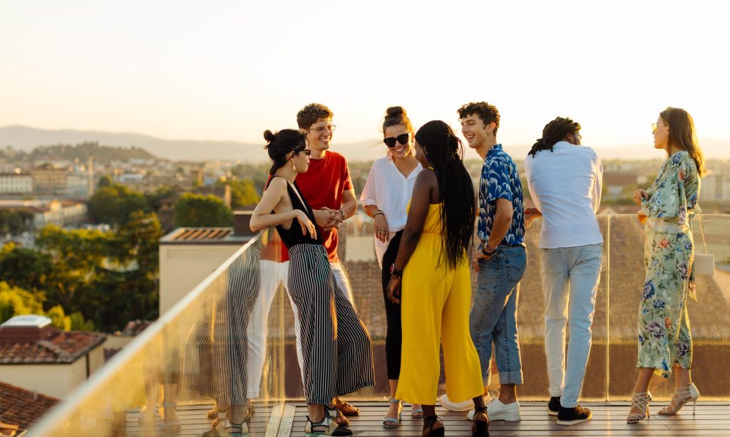 Frauen und Männer auf einer Rooftop Terrasse am Reden.