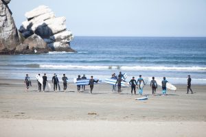 Gruppe von Leuten mit Surfboards auf dem Weg ins Wasser.