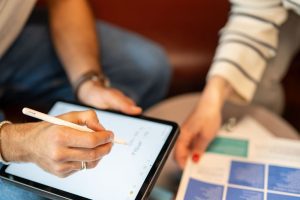 Travel planning with tablet and brochure, two people in a meeting.