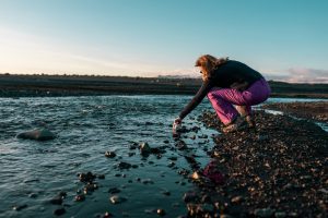 Woman at a black beach, near the water.
