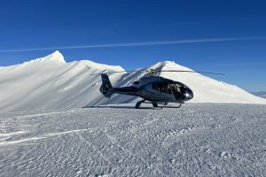 Helicopter in the snow, blue sky and sun.