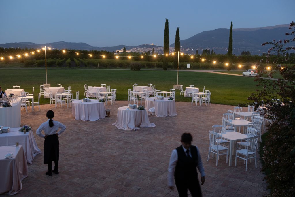 Event venue bei Dämmerung, weisse Tische und Stühle und Kellner.