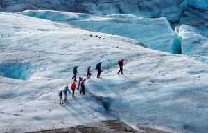 Group of people walking on glacier in Iceland, group trekking.