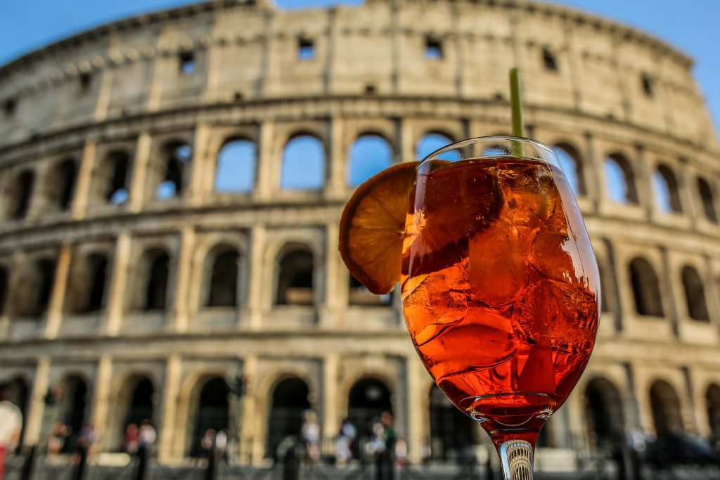 Kolosseum Rom mit Touristen davor und ein Aperol Spritz.