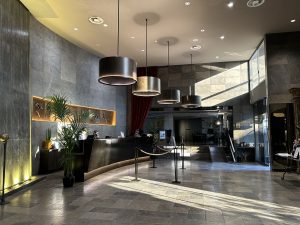 Gray hotel lobby with reception desk.
