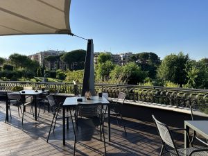 Terrace with parasols and black tables and chairs, view of the greenery.