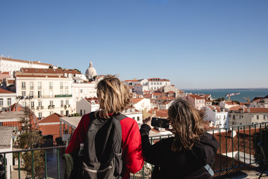 Two tourists overlooking Lisbon. Two woman, one with a black backpack.