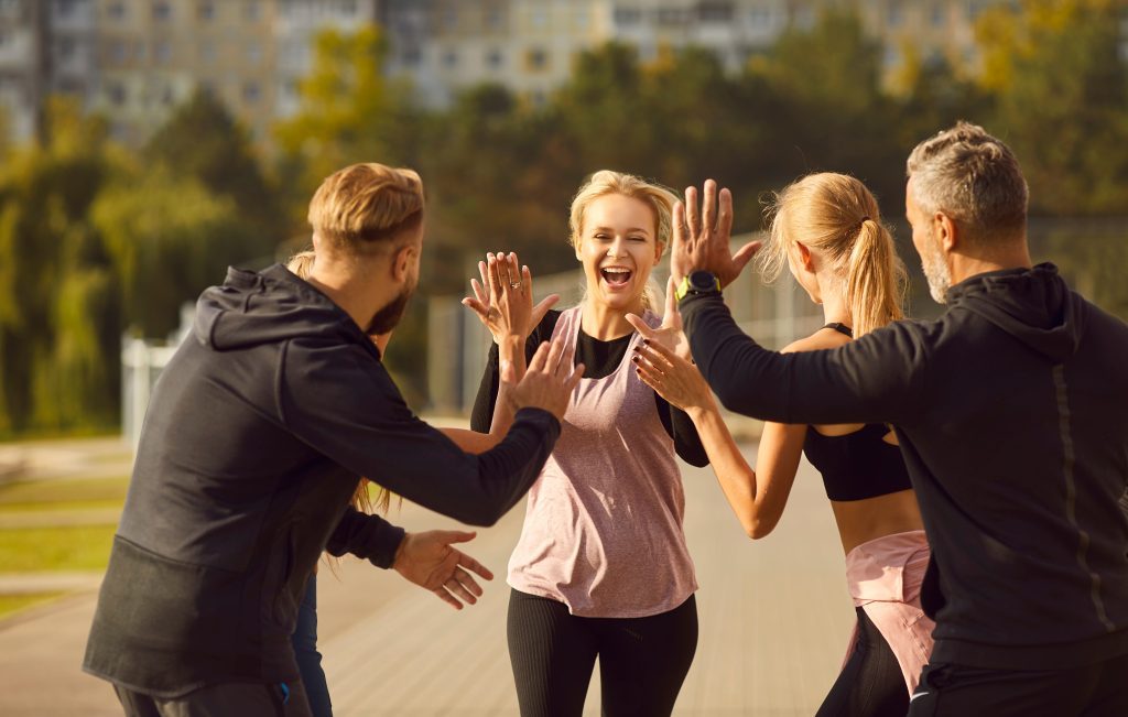 Team at sports activity outdoors, high-five.