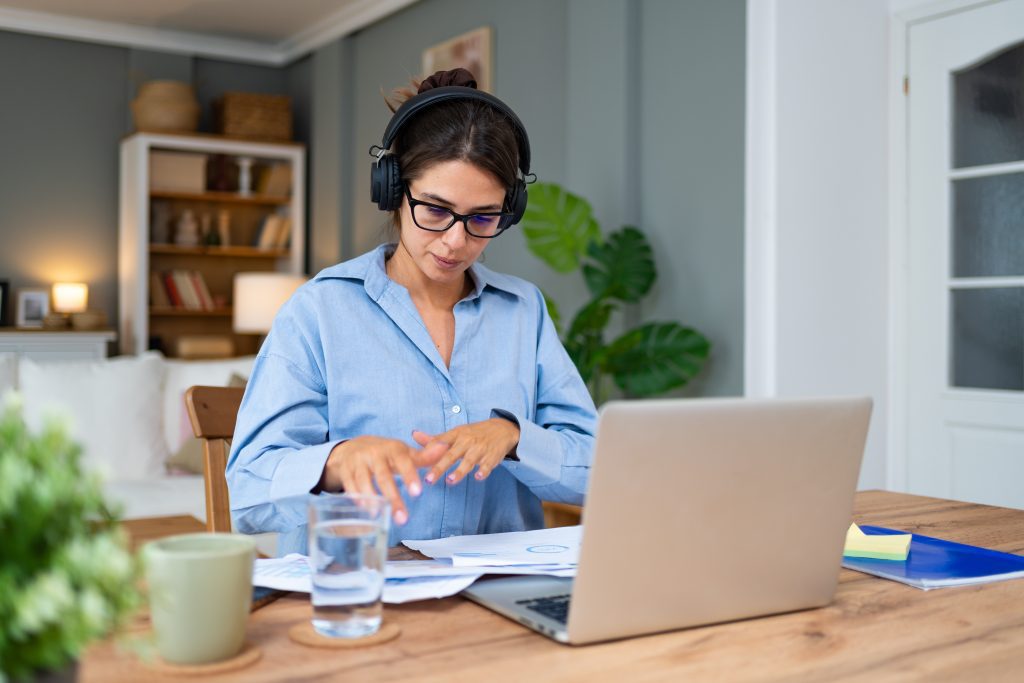 Woman in her home office with laptop on the desk.