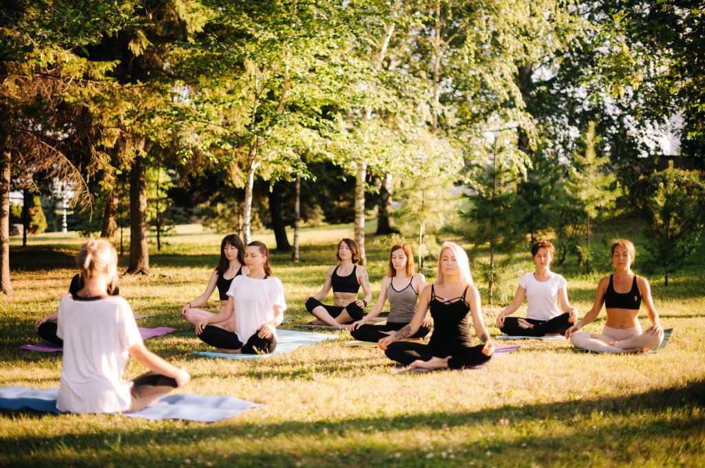 Meditation und Yoga im Park, Gruppe von Leuten sitzen im Grünen.
