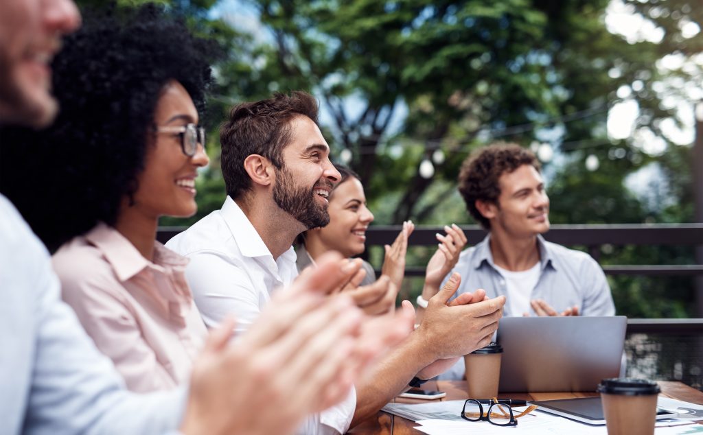 Business people applauding at a meeting, outdoors.