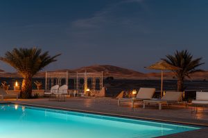 Luxury Desert Hotel with a Swimming pool and sand dunes in the background.