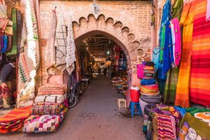 Marrakech market featuring handmade rugs and colorful fabrics.