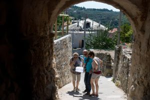 Group of people discussing clues during a treasure hunt in a small village, taking part in an interactive team-building activity in an authentic local setting.