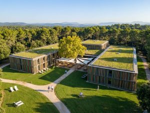 Low-rise eco hotel with a planted green roof set among lawns and trees outside Barcelona
