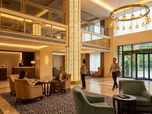 Elegant Lisbon hotel lobby lounge with green upholstered seating, warm wood panelling and large windows