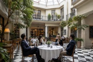 Atrium restaurant in Berlin with a black and white chequered floor, white linen tables and a glass roof