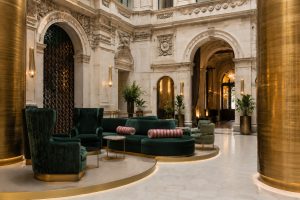 Boutique hotel lobby with marble arches, columns and green velvet armchairs under warm lighting