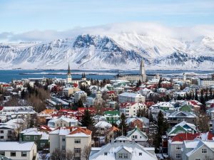 Colourful Icelandic city rooftops under snow with snow-capped mountains behind